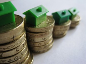 toy houses sitting on top of coin stacks