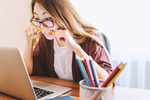 Frustrated woman biting pencil in office